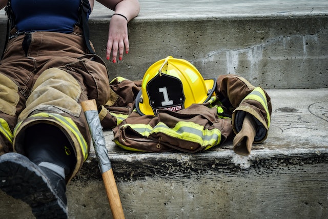 firefighter sitting down on some steps with their hat next to them