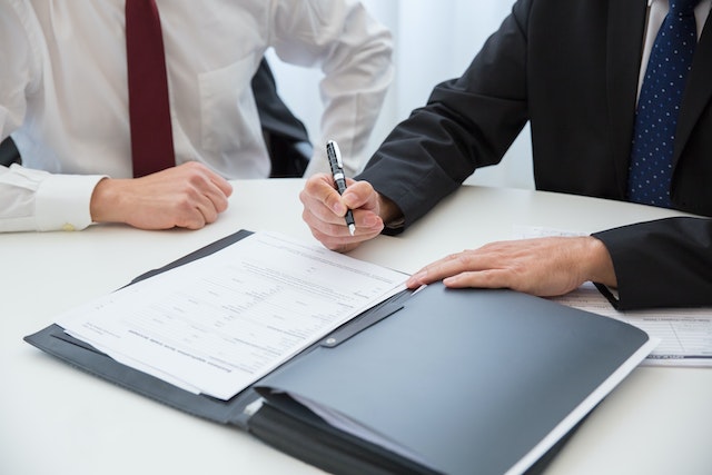 a person signing a lease document as someone else observes it