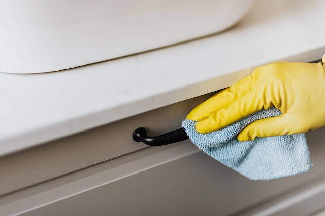 hand in a yellow glove cleaning off a black handle