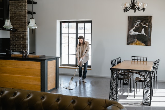 person mopping their floors in an open-concept kitchen and living room