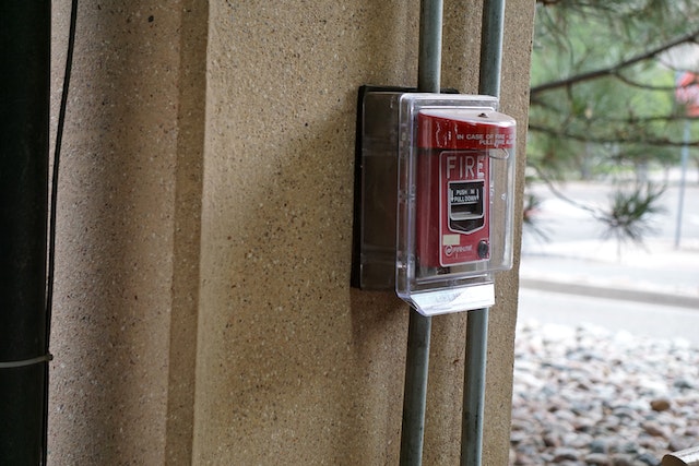a red fire alarm behind a protective plastic case